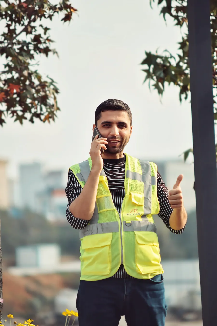 Trabajador de la construcción sonriendo mientras responde el teléfono en obra